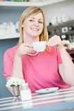 A young woman sitting in a cafe drinking tea