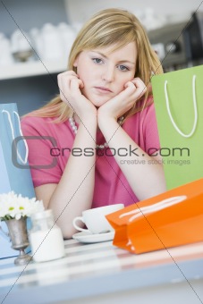 A young woman sitting in a cafe with shopping bags