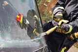 Firefighters breaking a car windscreen to help a car crash victi