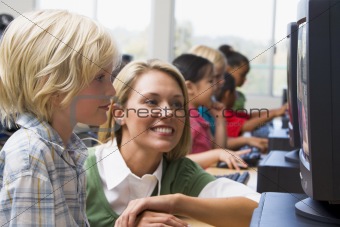 Teacher helping kindergarten children learn how to use computers