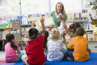 Kindergarten teacher reading to children in library