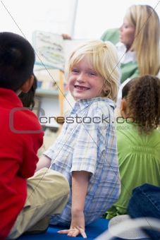 Kindergarten teacher reading to children in library, boy looking