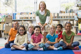 Kindergarten teacher sitting with children in library