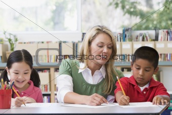 Kindergarten teacher helping students with writing skills