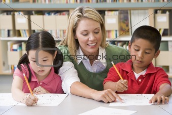 Kindergarten teacher helping students with writing skills