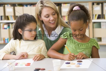 Kindergarten teacher sitting with students in art class