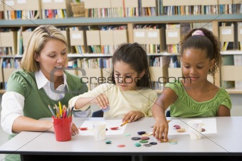 Kindergarten teacher sitting with students in art class