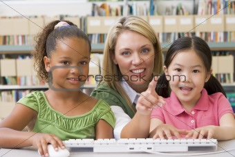 Kindergarten teacher sitting with children at computer