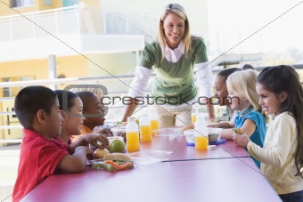 Kindergarten teacher supervising children eating lunch