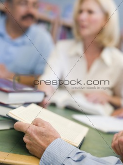 Mature students studying in library, focus on hands holding book