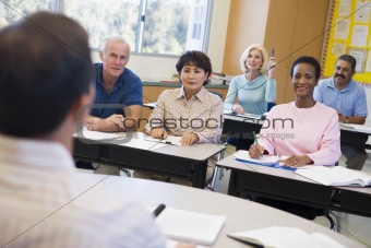 Mature female student raising hand in class