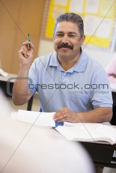 Mature male student raising hand in class