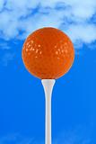 Orange golf ball against blue sky