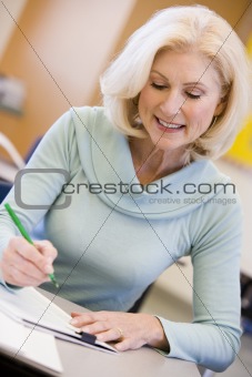 Mature female student writing in class