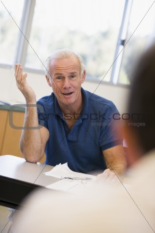 Mature male student gesturing in class