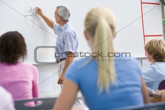 A teacher talks to school children in a high school class