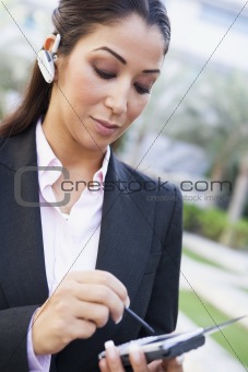 Businesswoman using PDA and earpiece