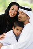 A Middle Eastern couple and their son sitting in a park