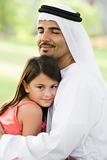 A Middle Eastern man and his daughter sitting in a park