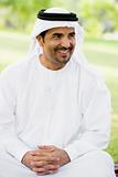 A Middle Eastern man sitting in a park
