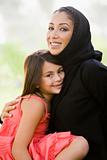 A Middle Eastern woman and her daughter sitting in a park