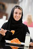 A Middle Eastern woman enjoying a meal in a restaurant