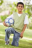 Boy holding football in park