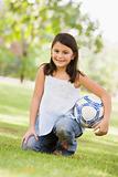Girl holding football in park