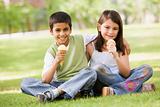 Two children eating ice cream in park