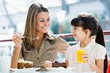 Mother and daughter eating cake in cafe