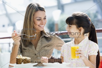 Mother and daughter eating cake in cafe