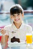Young girl eating chocolate cake in cafe