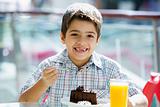 Young boy eating chocolate cake in cafe