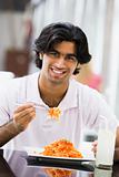 Man eating plate of pasta at cafe