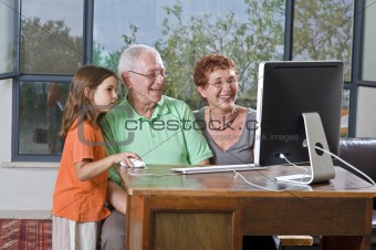grandparents and granddaughter with computer
