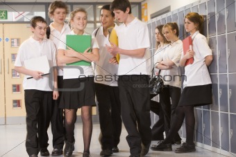 Teenage boys clustered around a girl at school