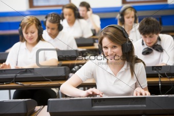 Schoolchildren practicing on a keyboard in music class