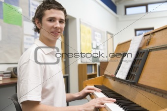 Schoolboy playing piano in music class