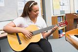 Schoolgirl playing guitar in music class