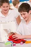 Schoolchildren using a sewing machine in sewing class
