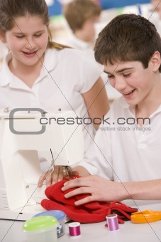 Schoolchildren using a sewing machine in sewing class