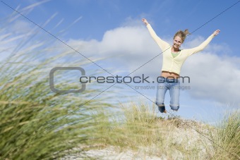 Young woman jumping amongst dunes