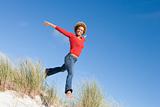 Young woman jumping amongst sand dunes