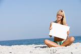 Woman on beach holding blank card