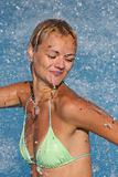 Young beautiful happy smiling tanned blond woman in bikini at rain or summer shower on sea beach