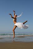 Beautiful young woman jumping on a beach in Greece