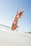 Young woman leaping on beach
