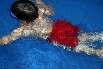 Boy in pool with red swimming trunks