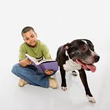 Boy reading book with dog.