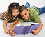 Brother and sister reading book together.